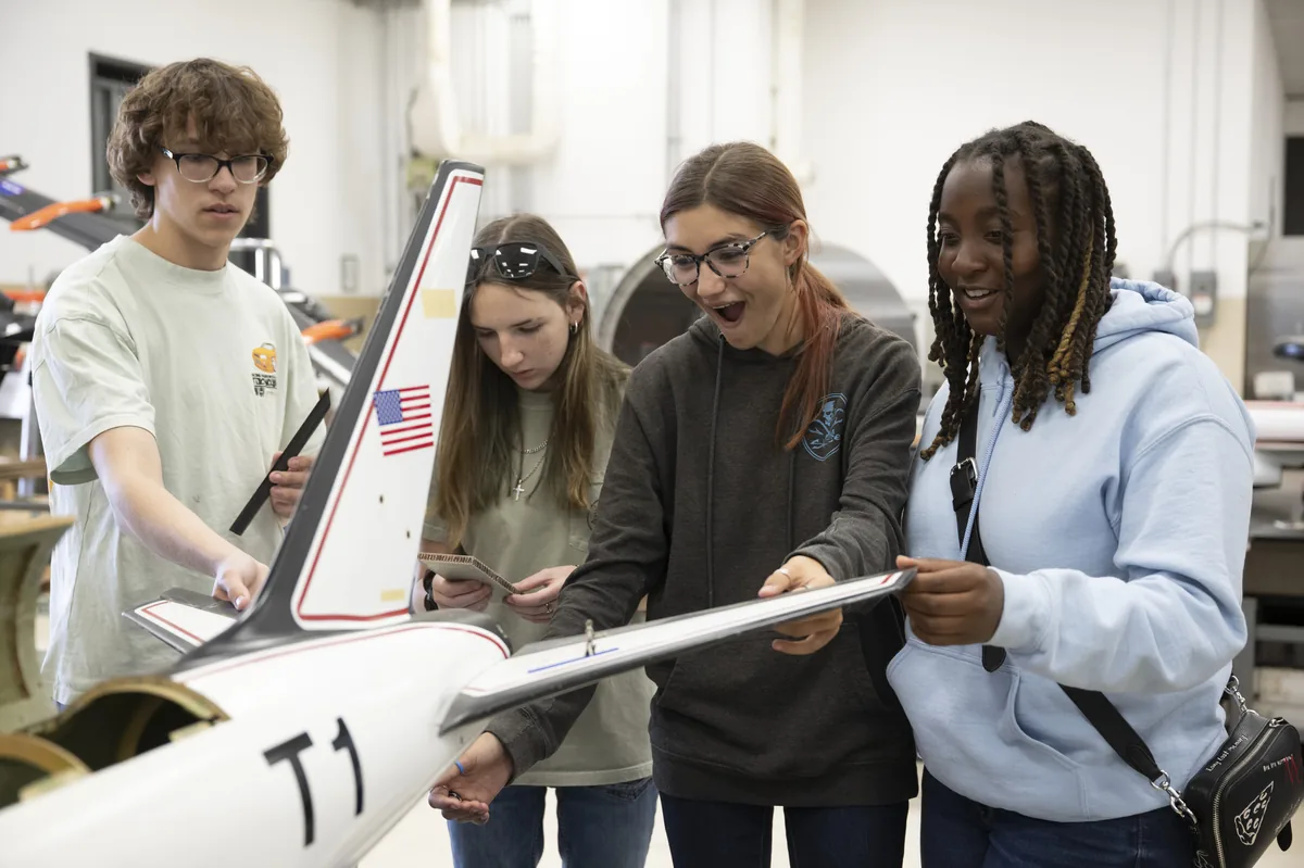 En visite dans un centre de recherche de la NASA, des lycéens et des étudiants examinent la maquette d'un avion de recherche. Photo : NASA, domaine public