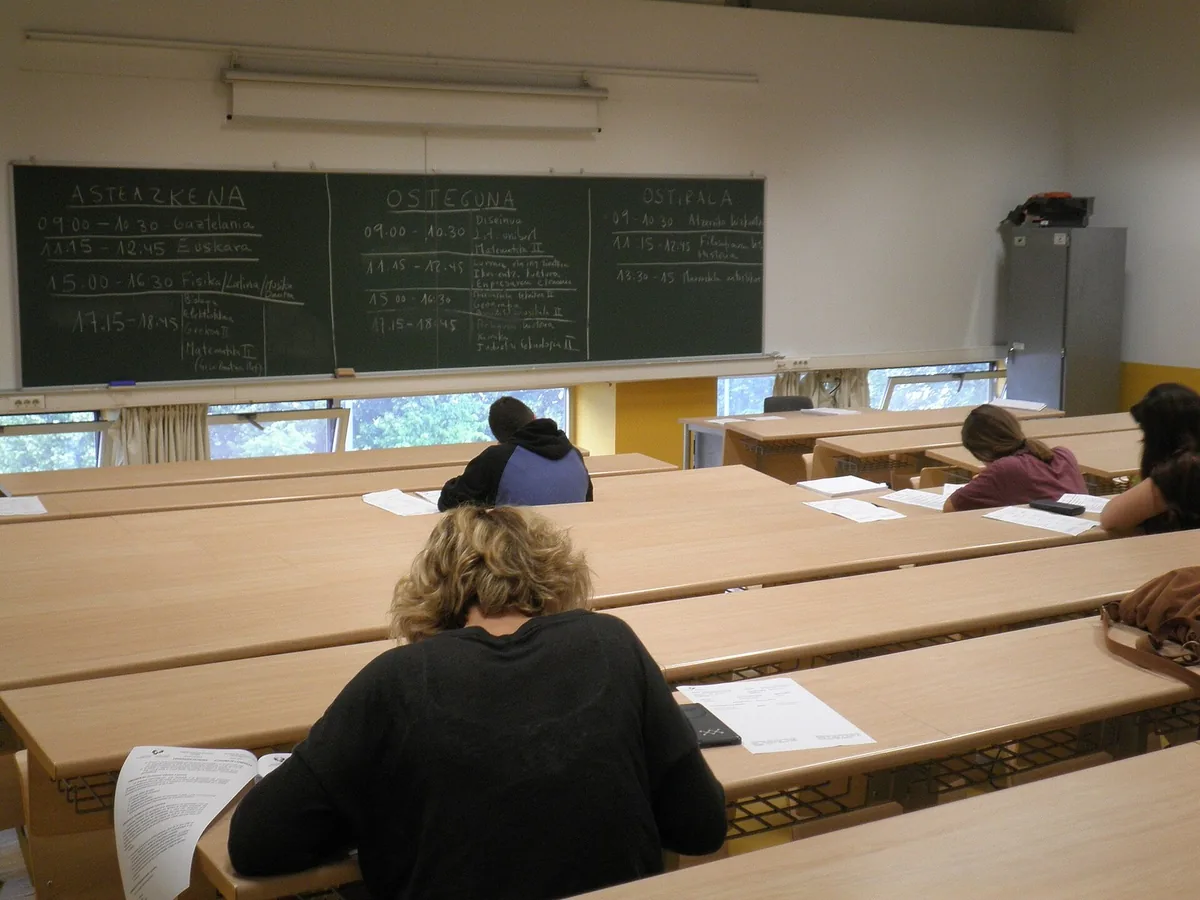 Le jour d'un examen d'entrée à l'université, à Saint-Sébastien : les candidats composent, l'horaire des épreuves au tableau. Photo : Joxemai, CC BY-SA 3.0