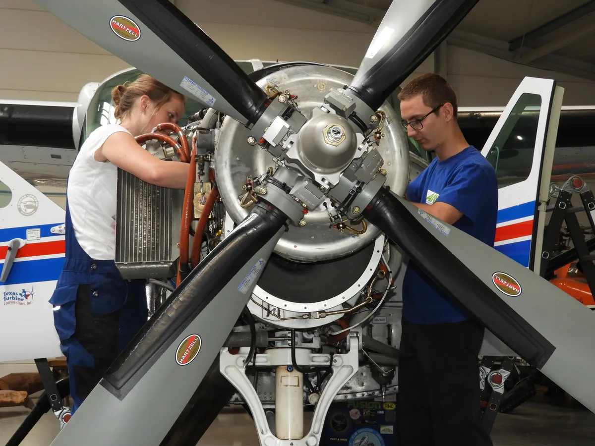 Dans un atelier de l'aéroport de Teuge, aux Pays-Bas, deux jeunes mécaniciens travaillent sur le moteur d'un avion à turbopropulseur. Photo : Peter F.A. van de Noort, CC BY-SA 4.0