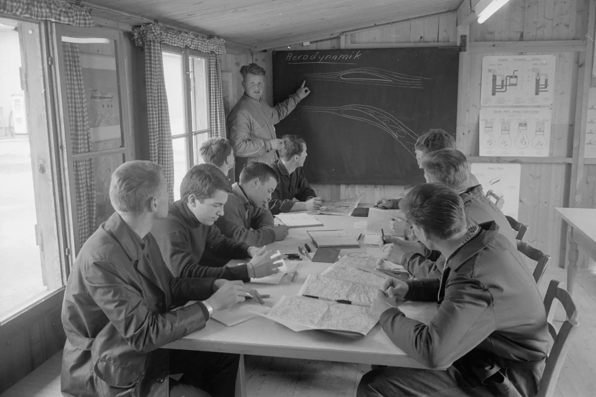 En Suisse, dans les années 1960, un instructeur dessine au tableau l'écoulement de l'air autour d'une aile pour de jeunes élèves pilotes. Photo : Kurt Salvisberg (ETH-Bibliothek Zürich), CC BY-SA 4.0