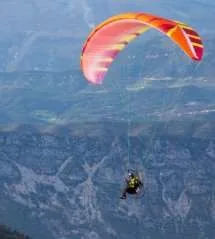 Paramoteur en vol au-dessus d’une vallée : c’est un parapente auquel on a ajouté un moteur à hélice porté sur le dos du pilote (la classe 1 des ULM)