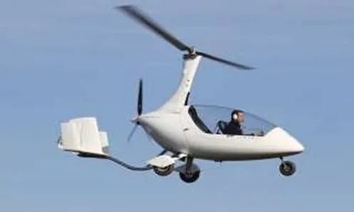 Autogire en vol de profil : un grand rotor libre tourne au-dessus de la cabine ouverte et assure la sustentation, tandis qu’une petite hélice propulsive entraînée par le moteur est placée derrière la cabine