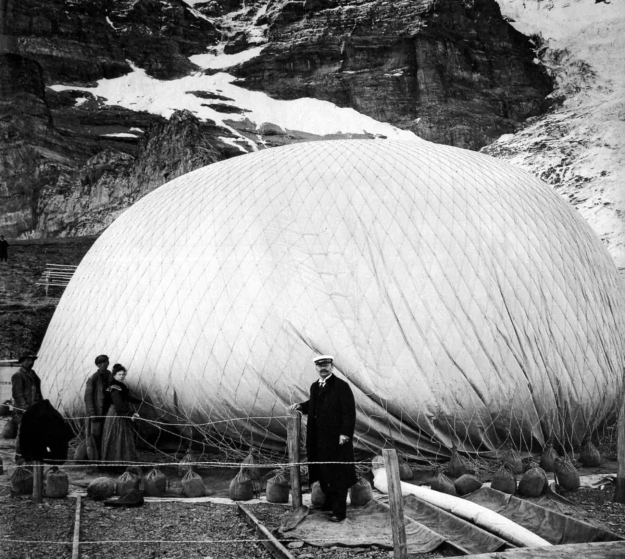Le ballon à gaz Stella d’Eduard Spelterini pendant son gonflement à l’hydrogène, au pied de l’Eiger, le 20 septembre 1904 : un filet coiffe l’enveloppe, et des sacs de sable accrochés tout autour la retiennent au sol ; en vol, c’est du sable comme celui-ci que le pilote largue pour monter. Photo : fonds Eduard Spelterini, domaine public