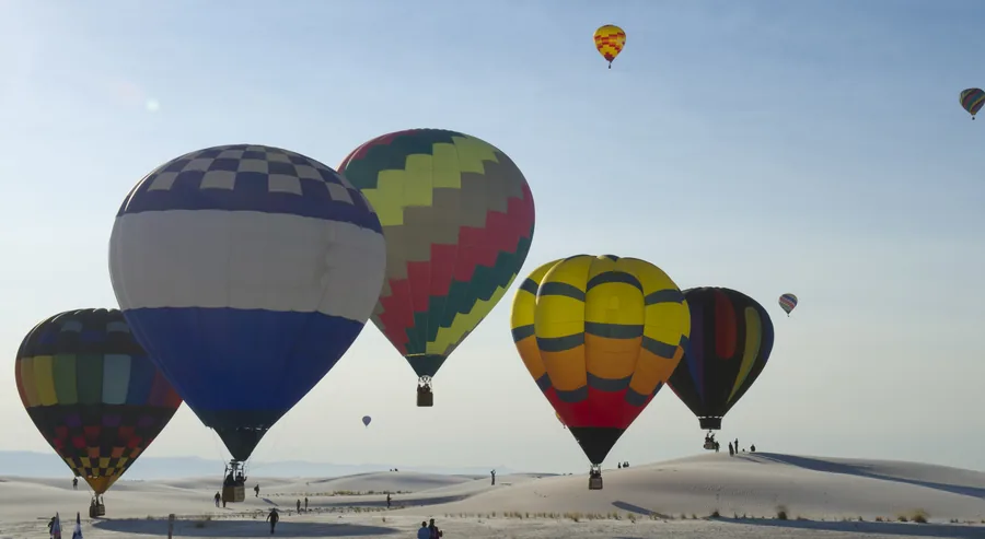 Montgolfières multicolores au décollage au-dessus des dunes blanches de White Sands, au Nouveau-Mexique : chaque enveloppe est ouverte vers le bas, où le brûleur chauffe l’air, et porte sa nacelle. Photo : US Air Force, domaine public
