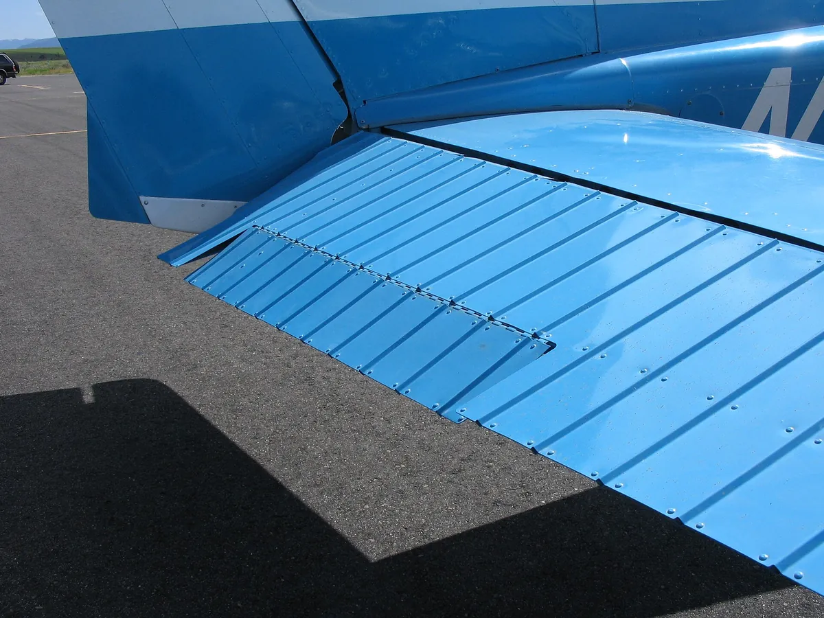 La gouverne de profondeur (elevator) d’un Cessna 172, vue de près : à son bord de fuite, sur la gauche, la petite surface montée sur sa propre charnière est le trim tab, le compensateur, qui maintient la gouverne en position sans que le pilote ait à forcer sur le manche. Photo : Elliebutton408, domaine public
