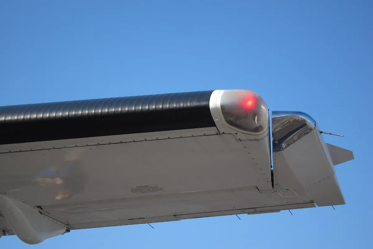 Le bout de l’aile gauche d’un ATR 72, vu de dessous : sous la bulle transparente de son extrémité, le feu de position rouge est allumé. Celui de l’aile droite, de l’autre côté, est vert. Photo : Olivier Cleynen, CC0